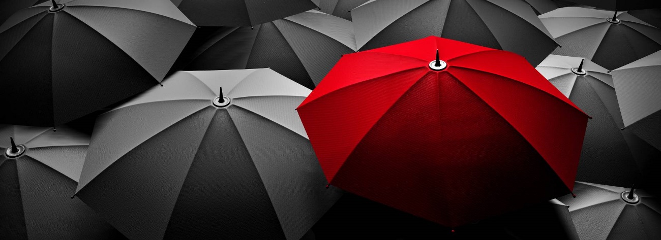 red umbrella standing out in a group of black umbrellas