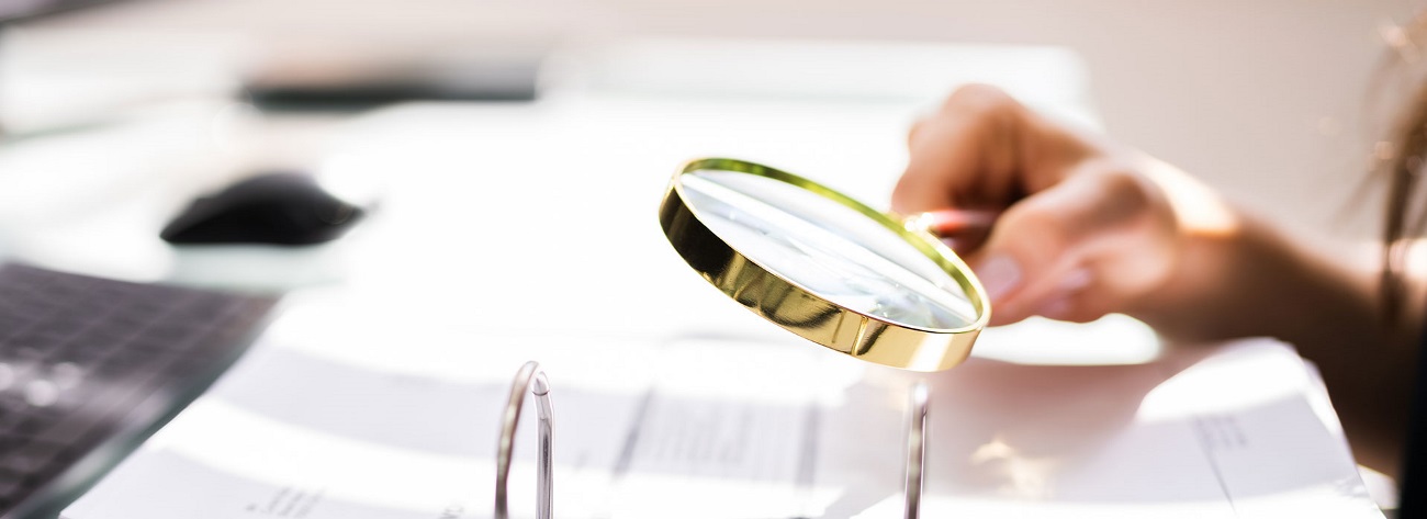 auditor investigating documents using magnifying glass