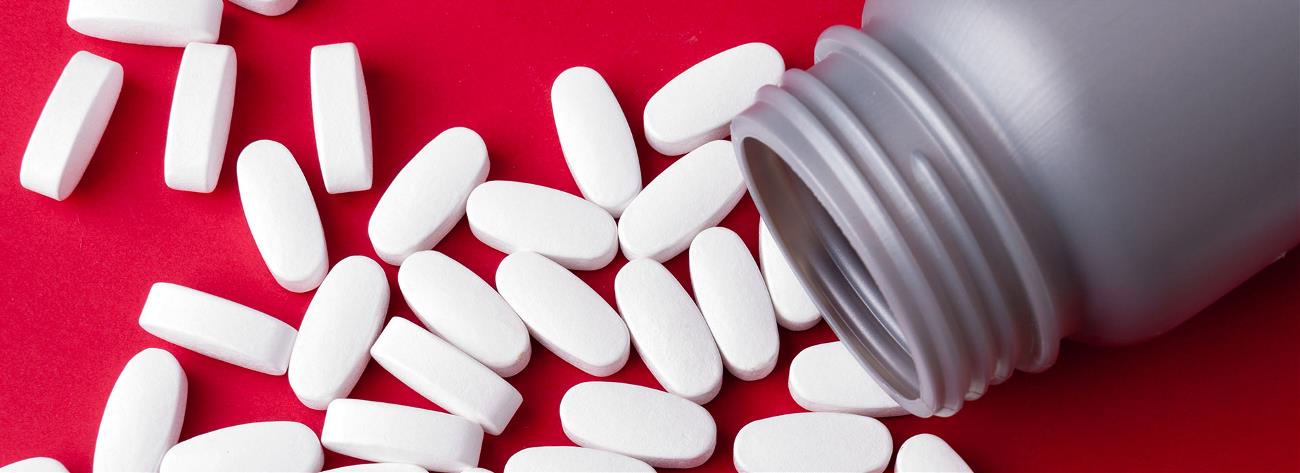 Close container of medicine in tablets on red background